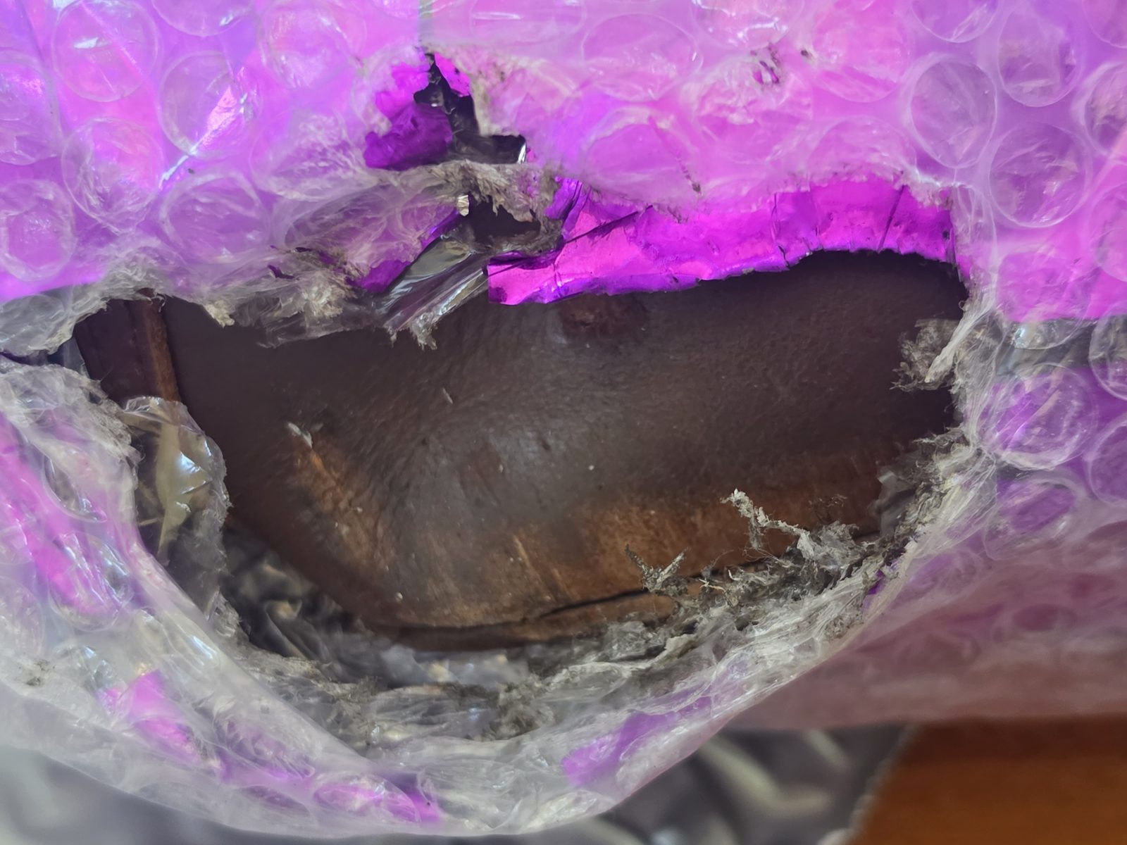 Shipping package torn open with a large hole through the wrapping